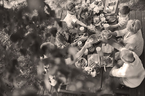 Family gathered around a wooden table for a meal outdoors